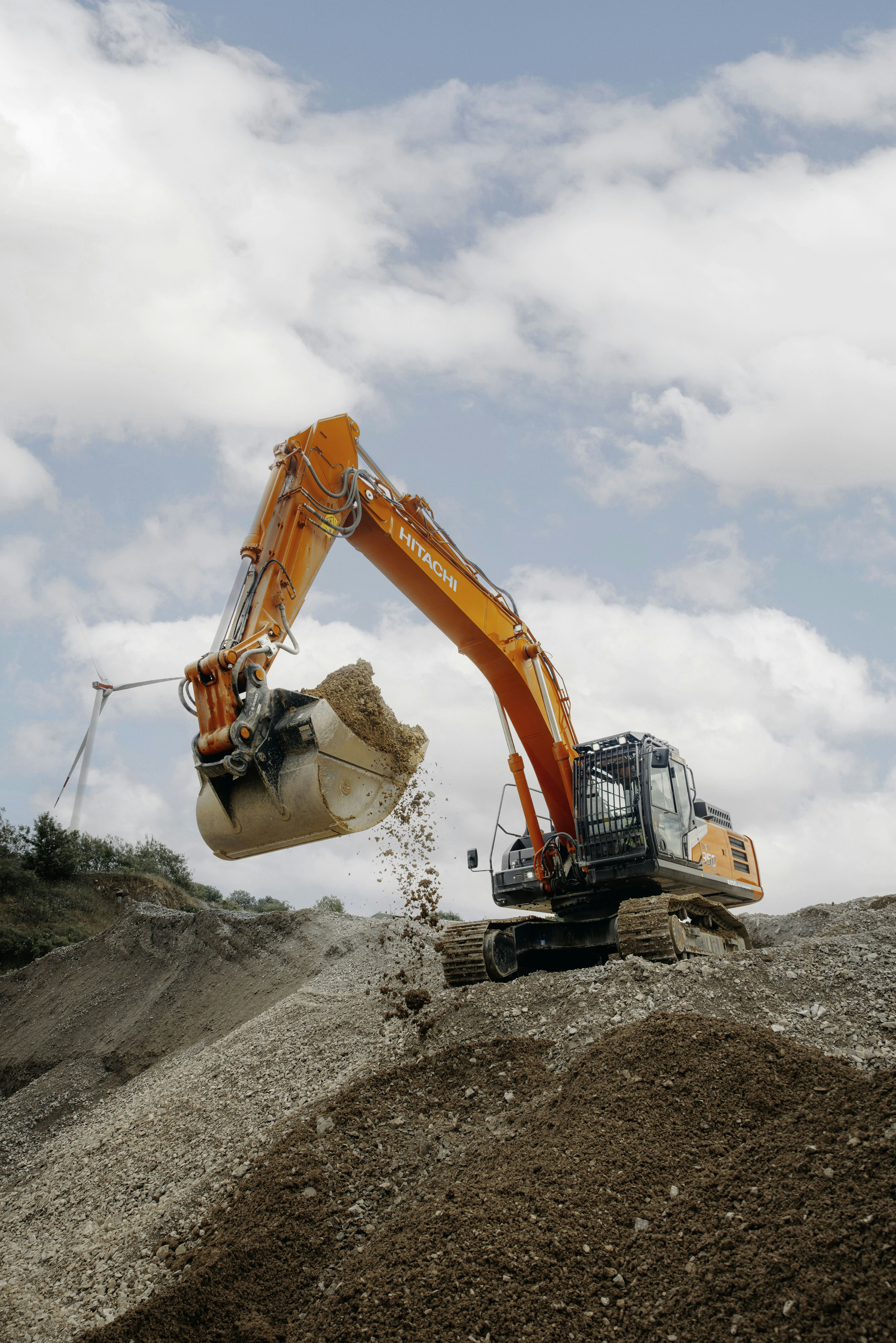 A construction truck is dumping dirt on a hill
