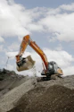 A construction truck is dumping dirt on a hill