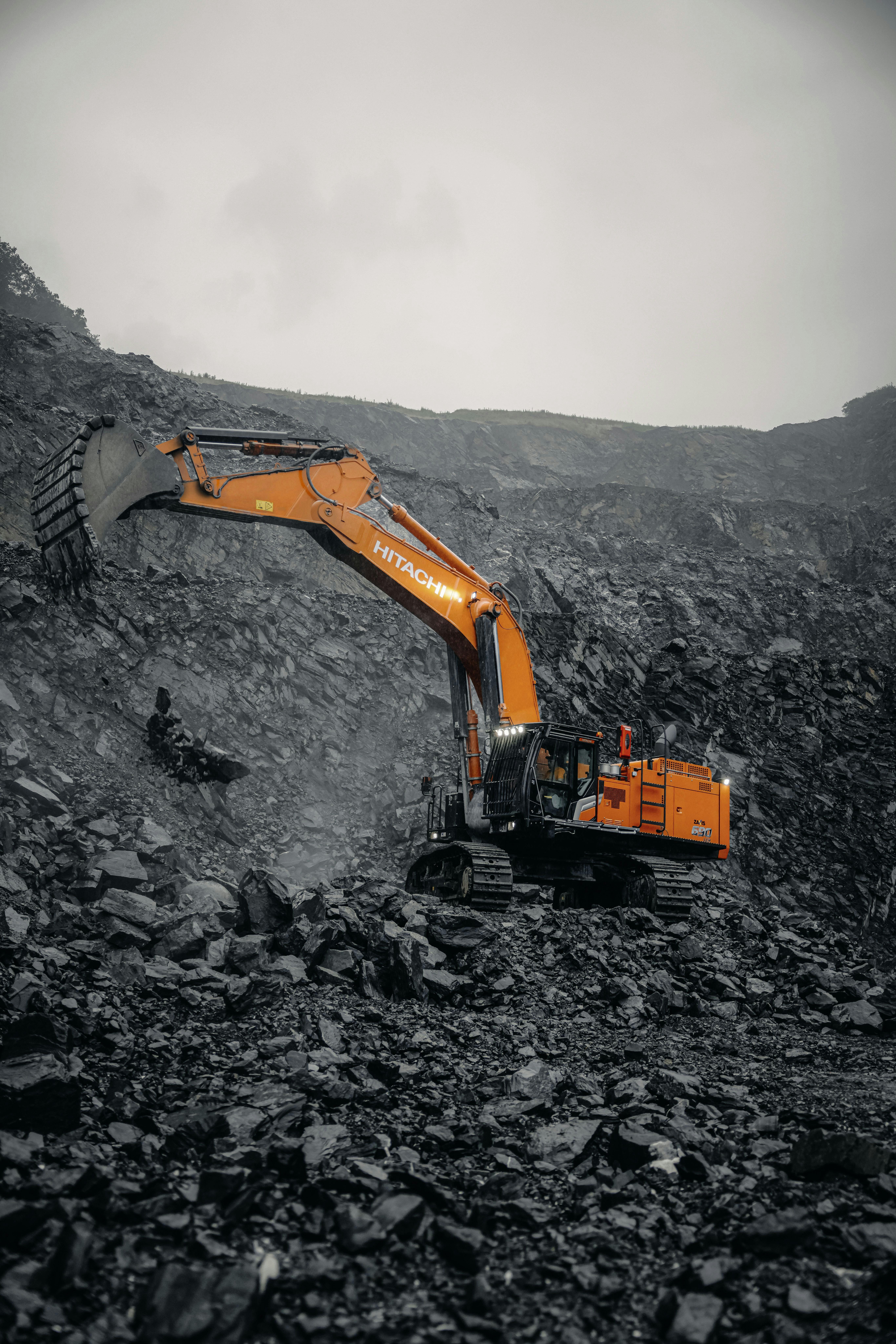 An orange excavator digging through a pile of rocks