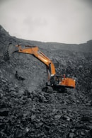 An orange excavator digging through a pile of rocks