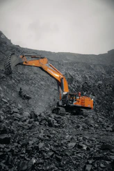 An orange excavator digging through a pile of rocks