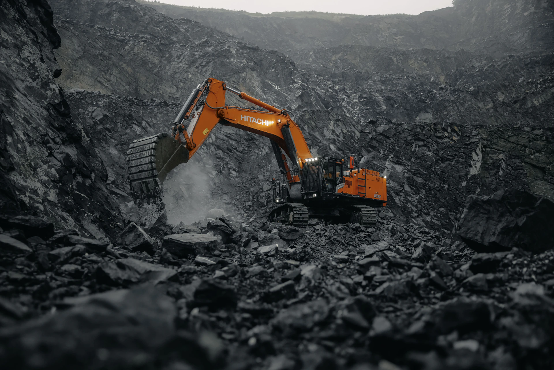 An orange excavator digging through a rocky area
