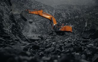 An orange excavator digging through a coal mine