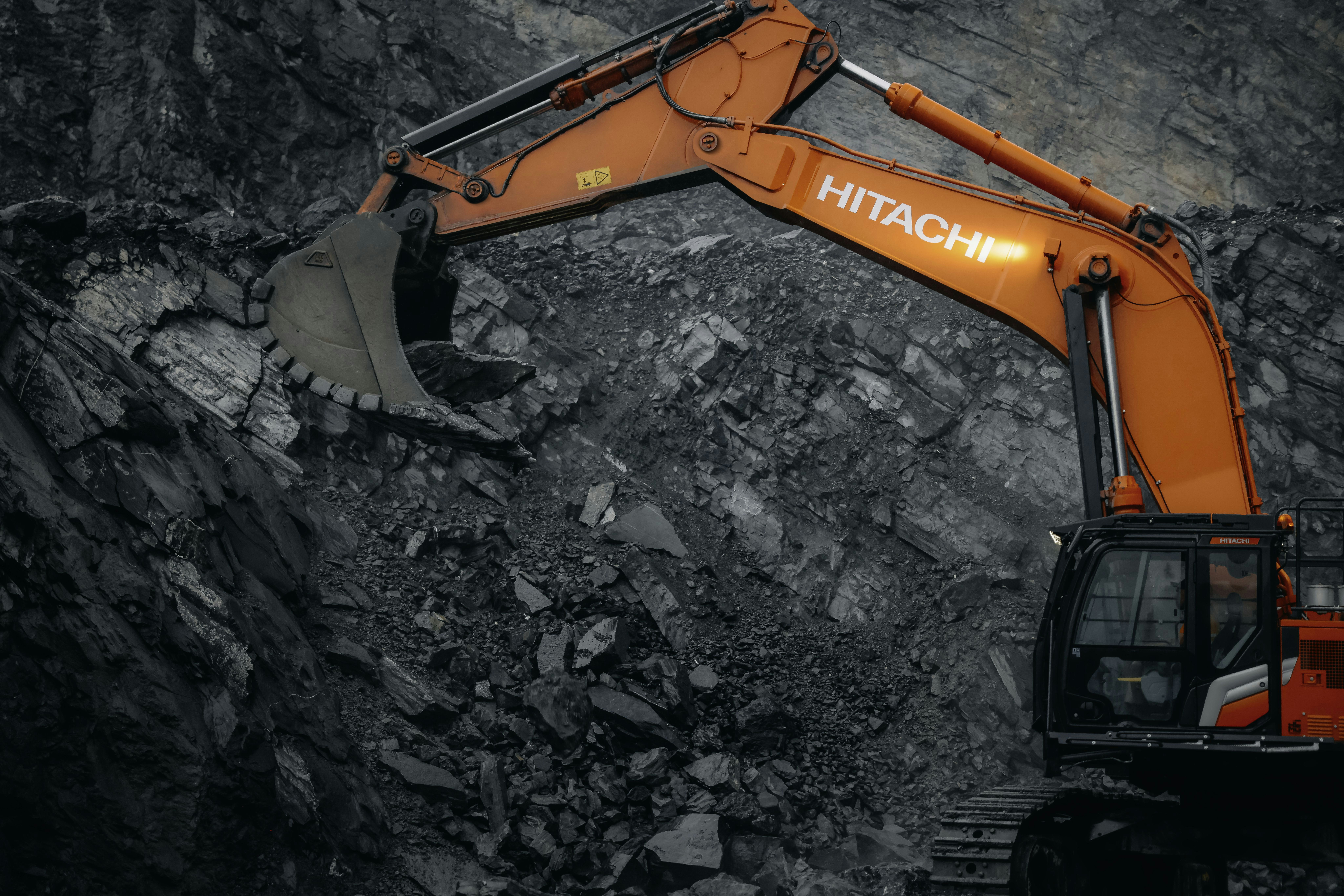 An orange excavator digging through a rocky area