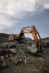 An orange excavator digging through a pile of rocks