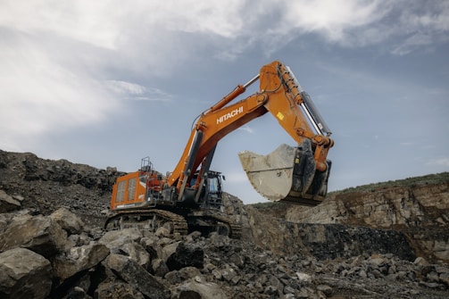 An orange excavator digging through a pile of rocks