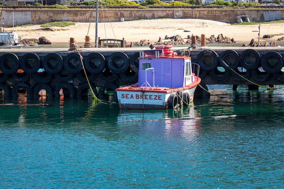 Quay wall lined with tyre fenders and a small vessel moored alongside