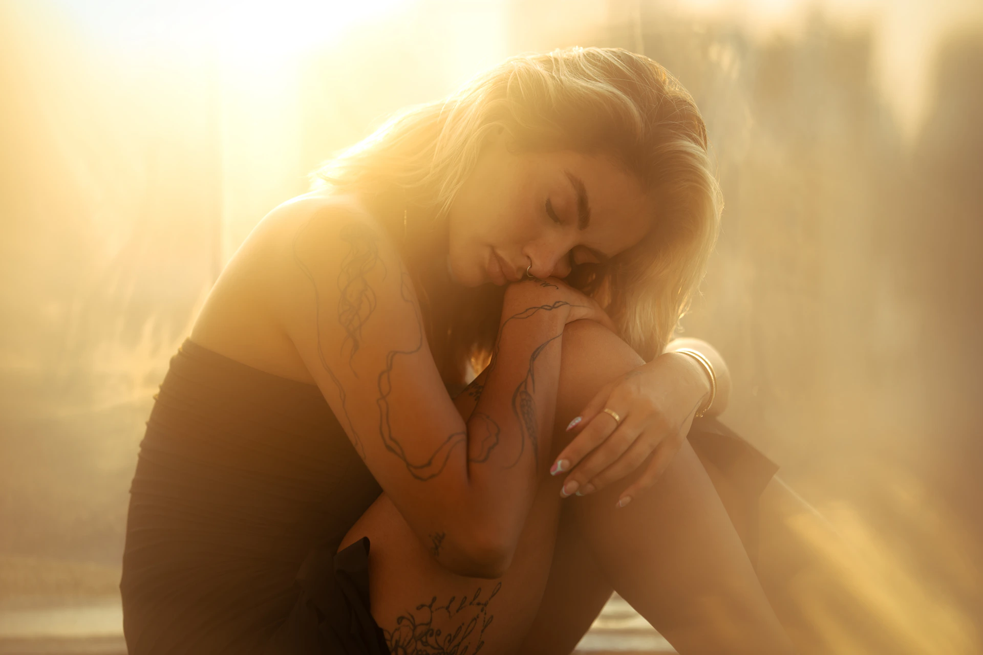 A woman sitting on a window sill with her hands on her face