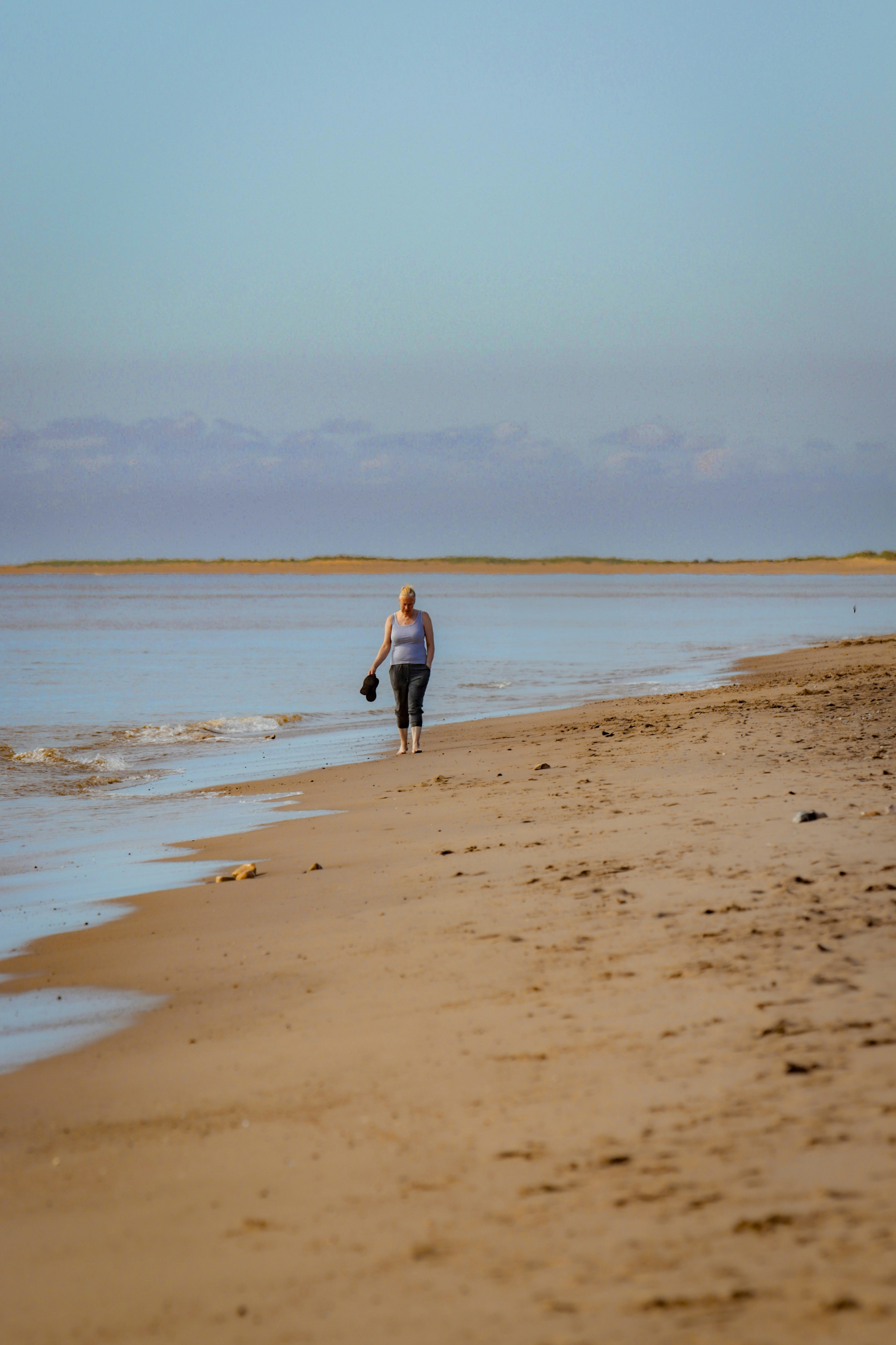 Una mujer caminando por una playa junto al océano