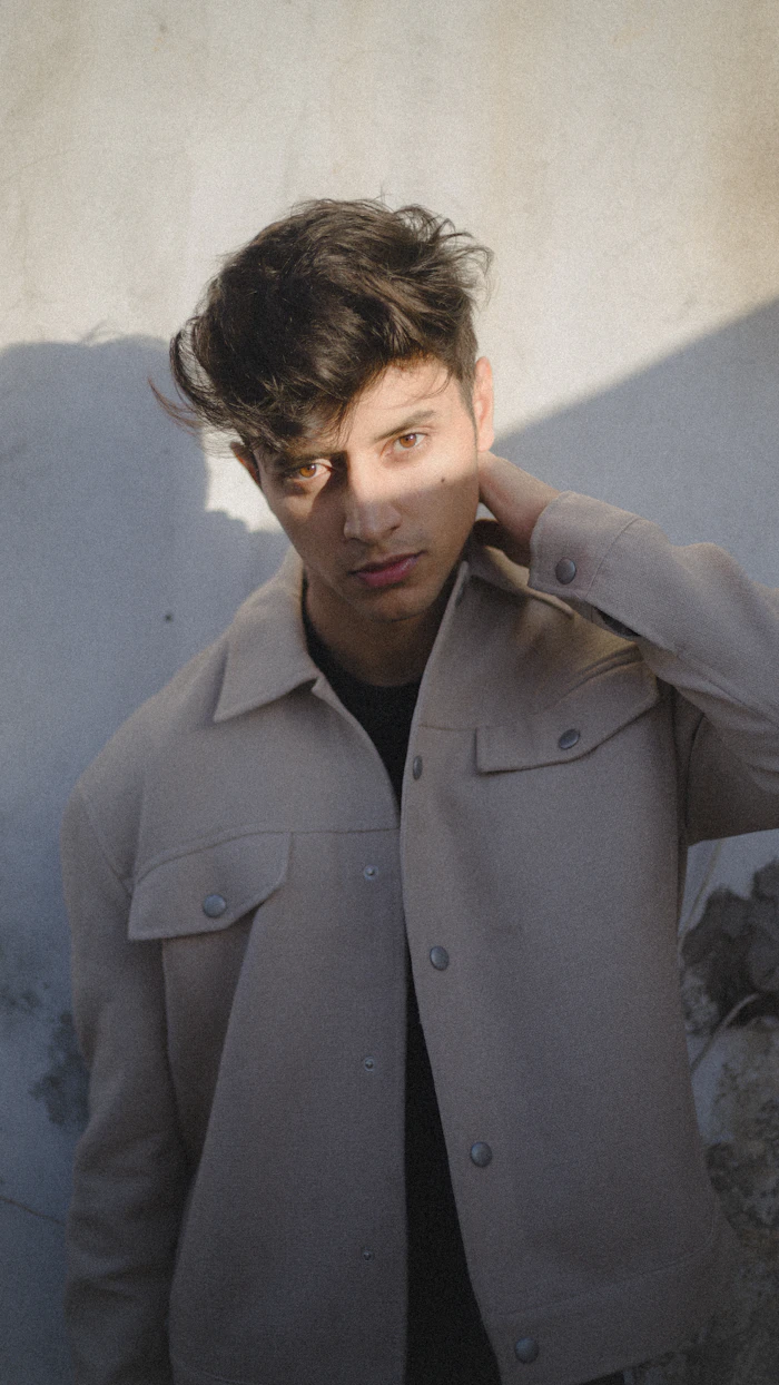 Man in a washed grey overshirt against a white wall
