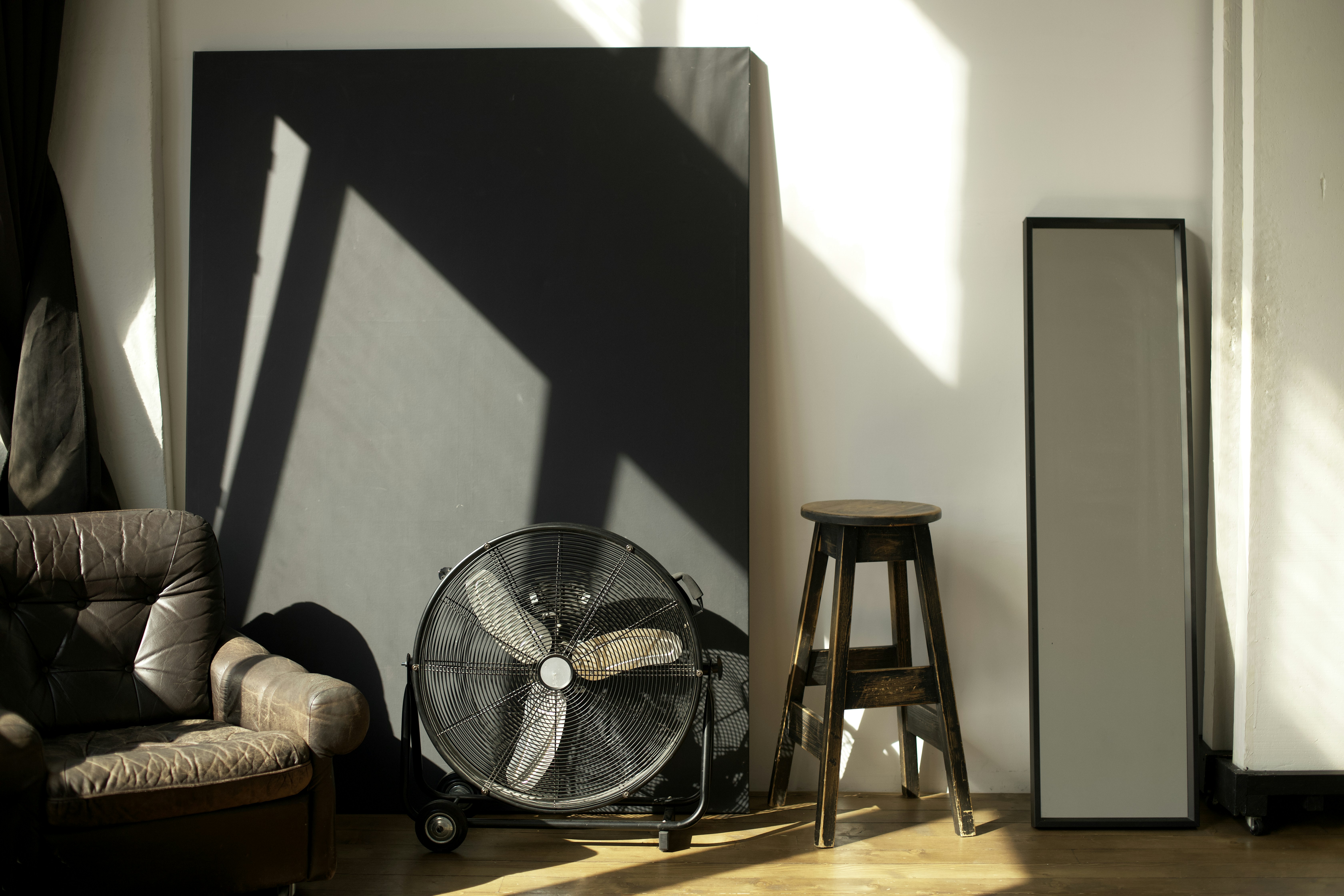 Portable fan setup in a living room with closed blinds and ice packs for emergency cooling while waiting for AC repair - 24 hour ac repair