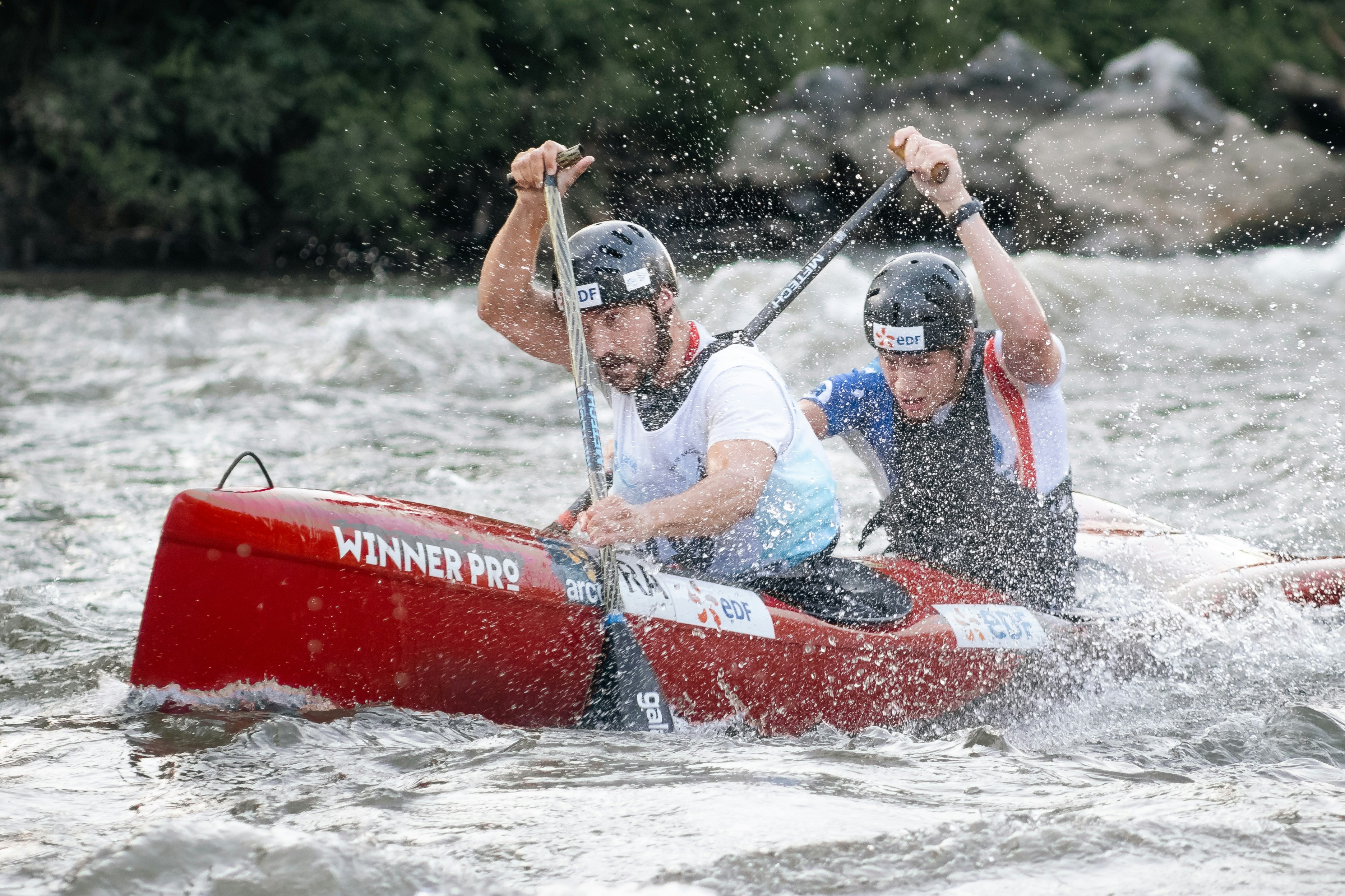 A couple of men riding on the back of a red boat photo – Free Brown ...