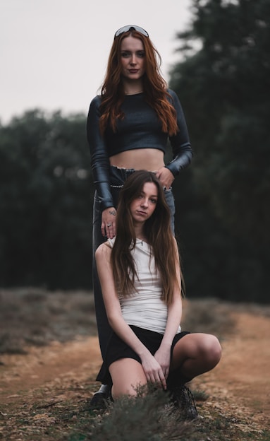Two young women are sitting on a hill