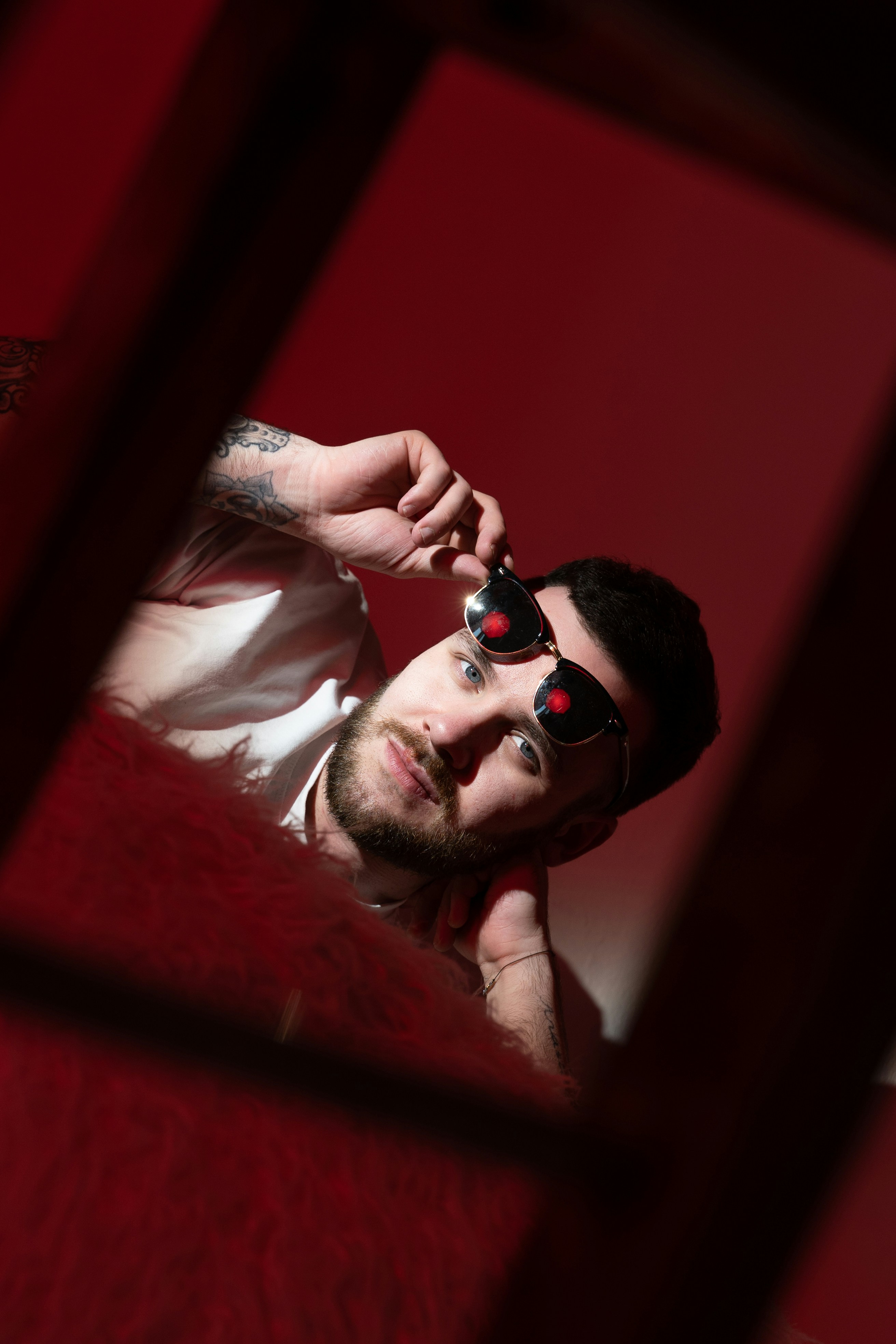 A man in a white shirt is taking a picture of himself in a mirror