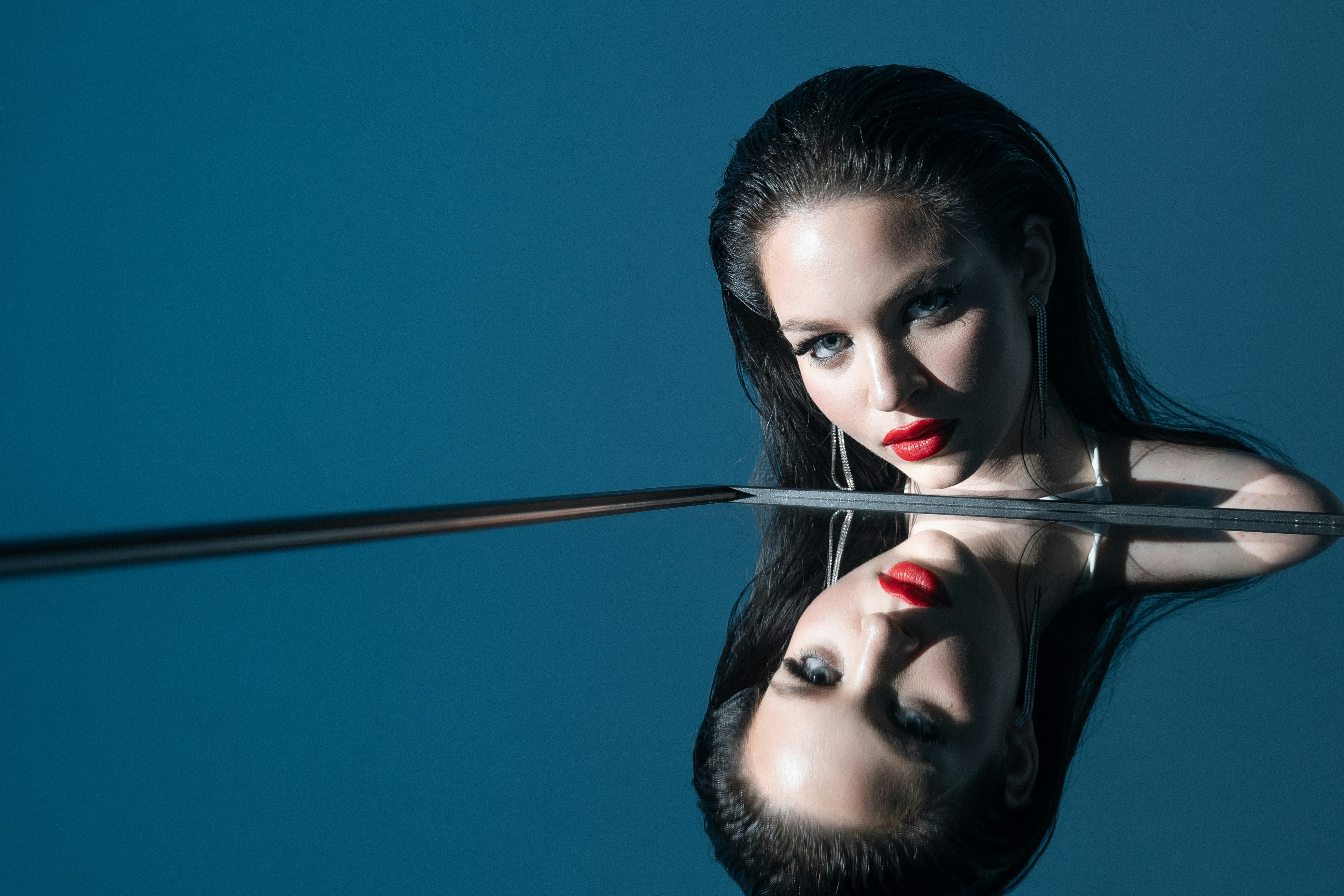 A woman holding a sword in front of her face