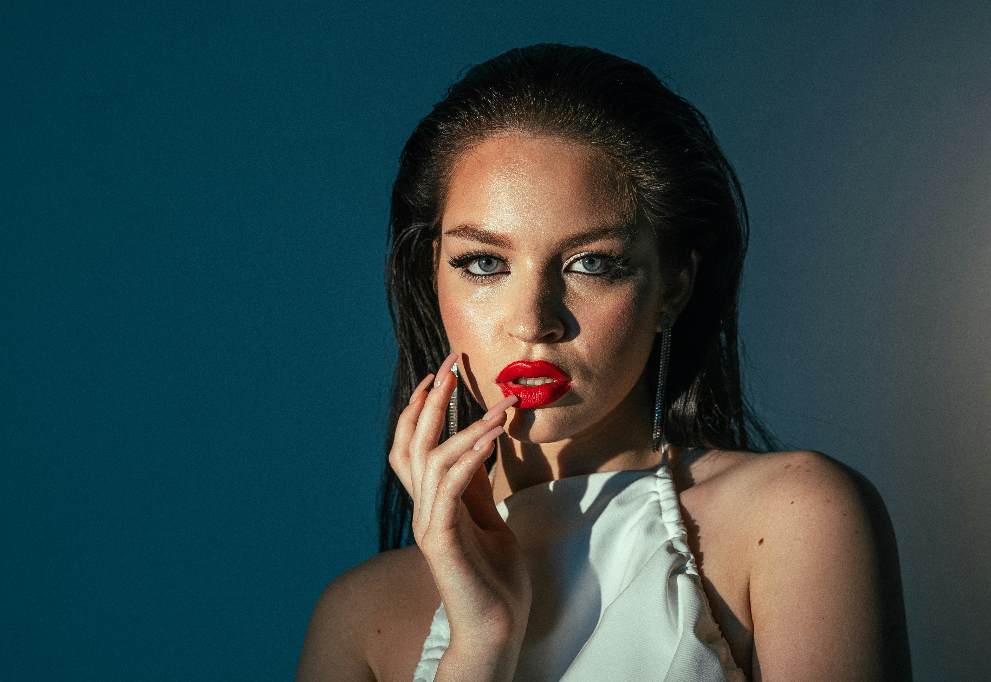 A woman in a white dress holding a red lipstick