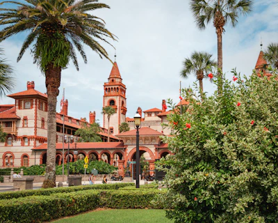 A large building in st augustine with a clock tower next to a lush green park