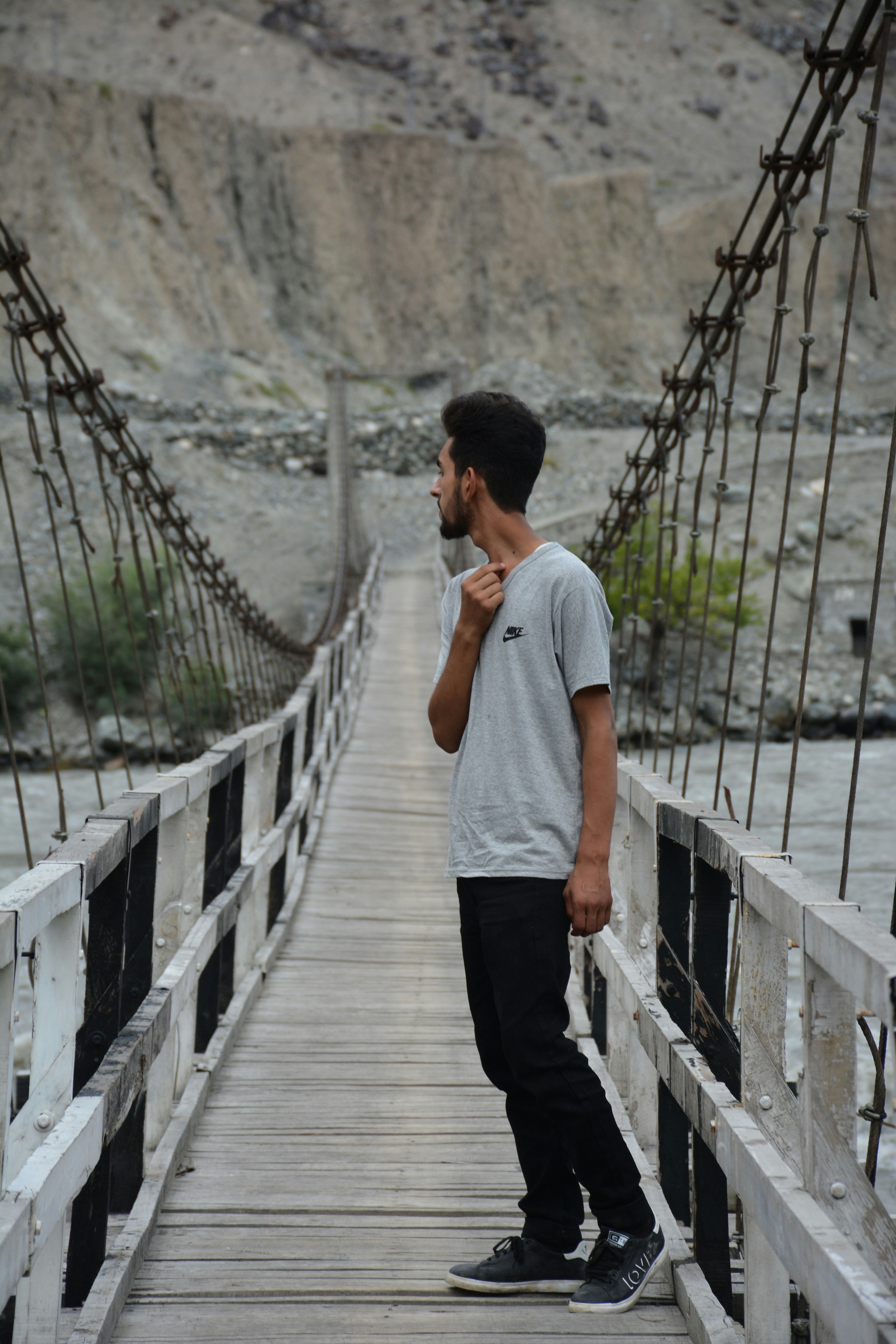 A man is standing on a bridge and talking on a cell phone