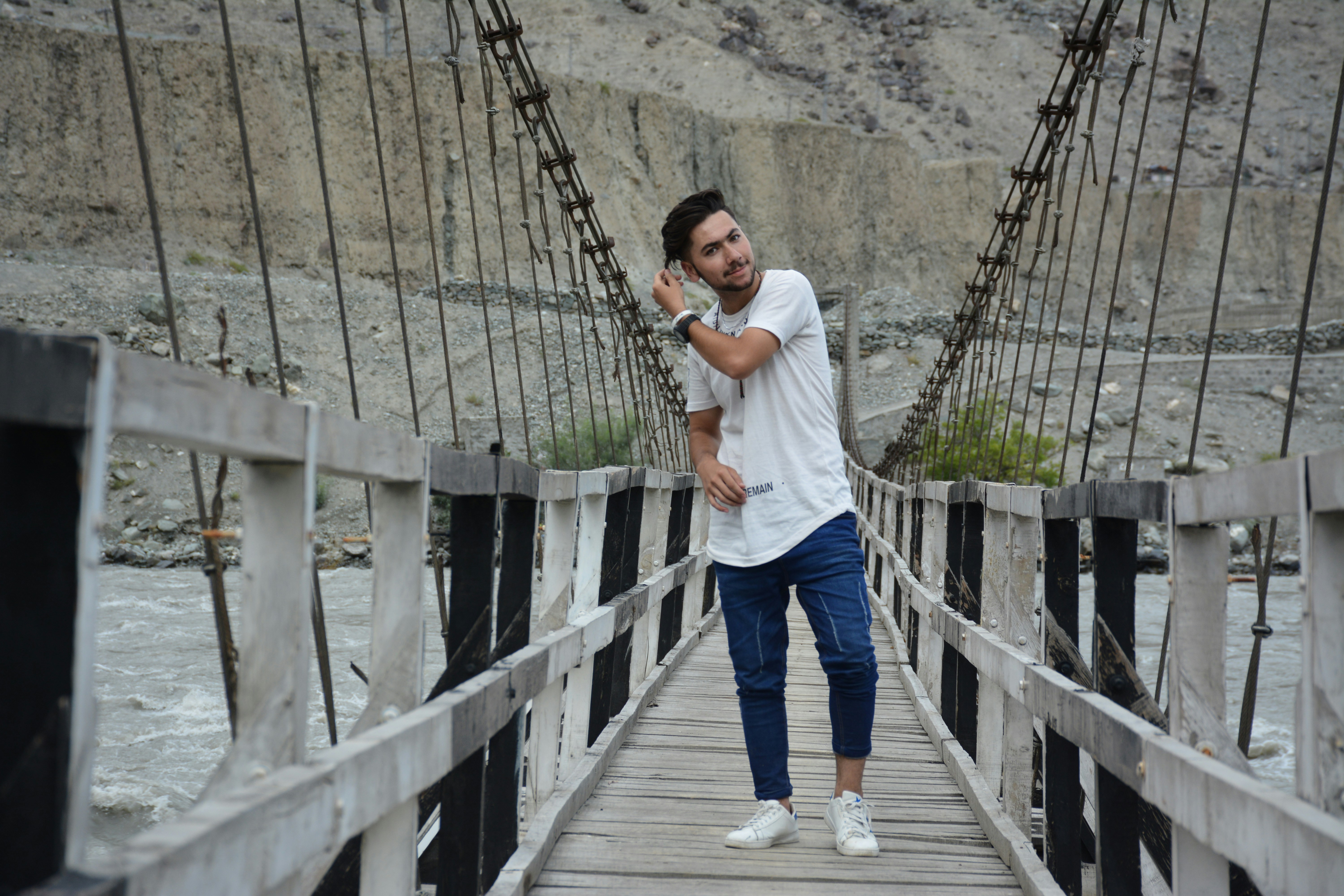 A man standing on a wooden bridge next to a river