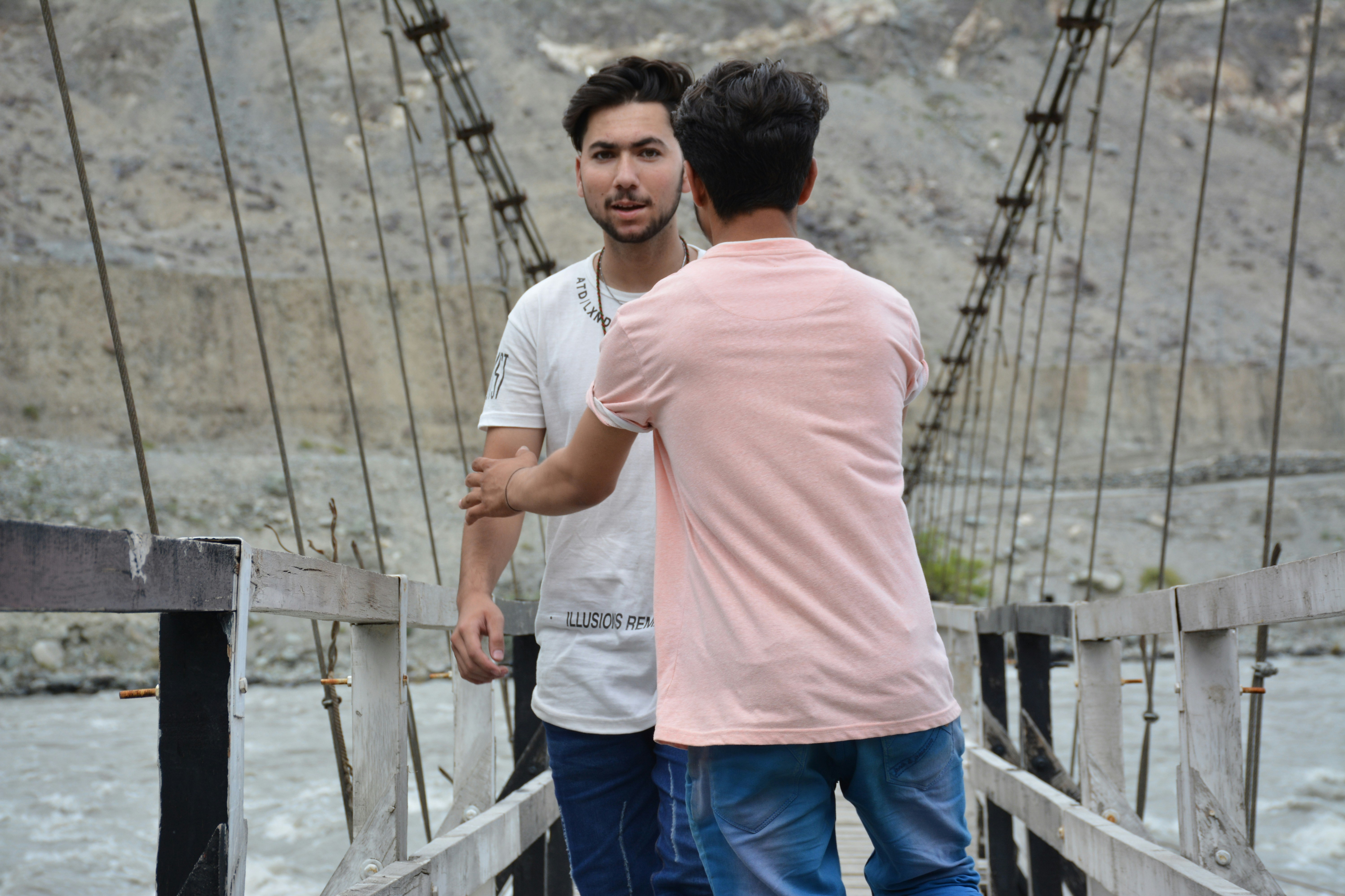 Two men standing on a bridge over a river