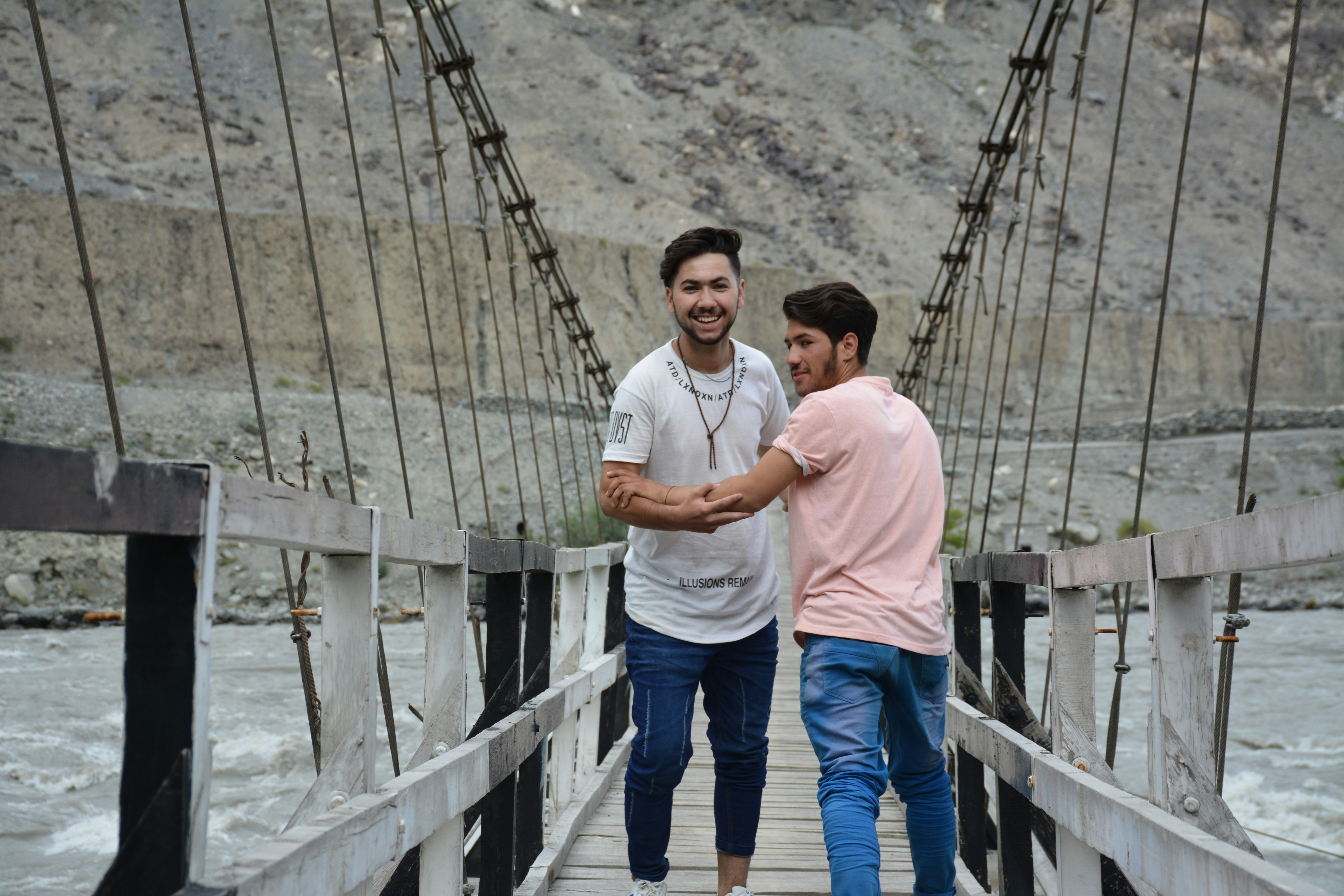 Two men walking across a bridge over a river
