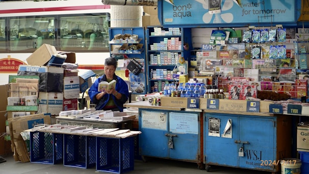 A man standing in front of a store filled with items
