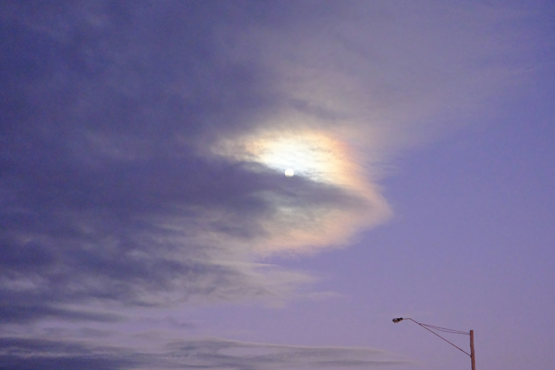 A street light and a street sign under a cloudy sky
