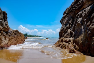 A sandy beach with rocks and water on a sunny day