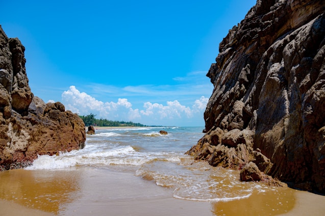 A sandy beach with rocks and water on a sunny day