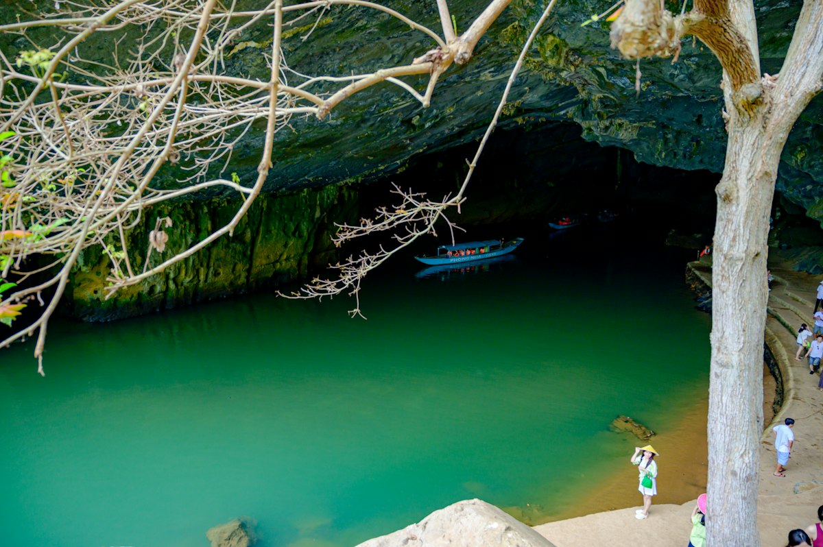 Forested limestone cliffs rising above a river at a Phong Nha cave mouth