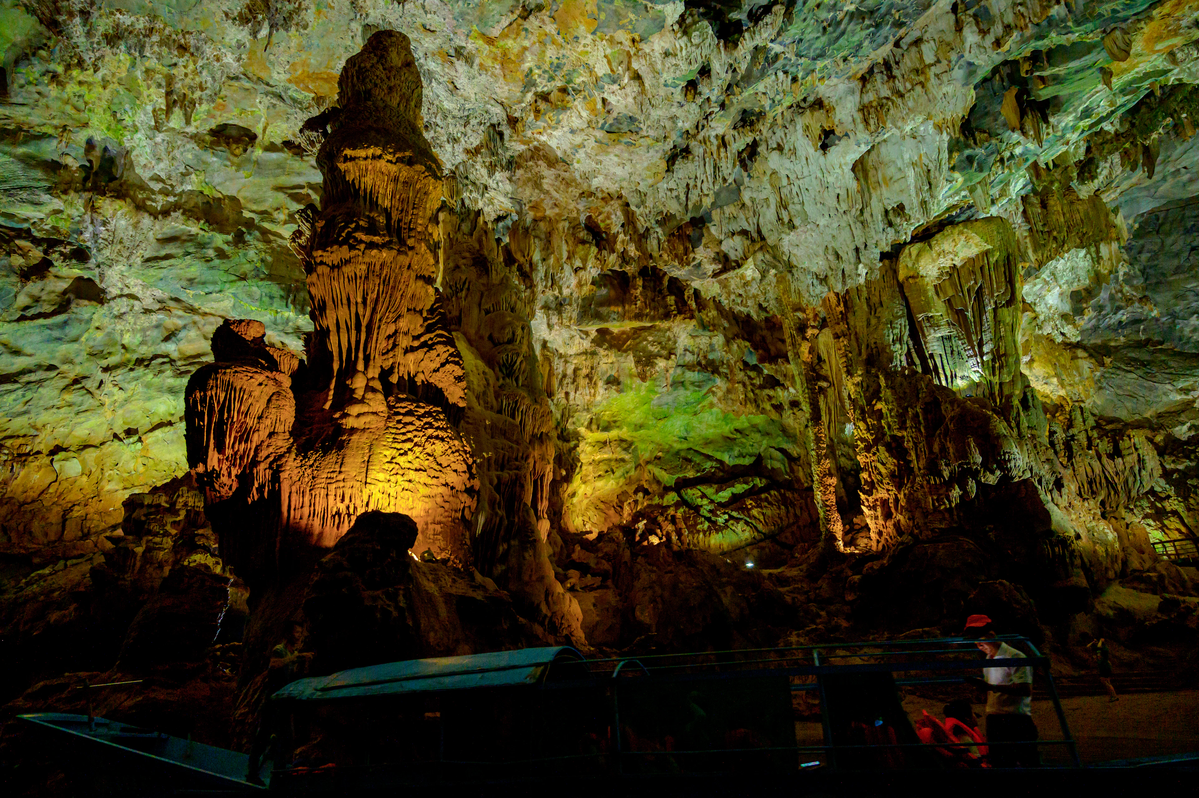 Softly lit stalagmites and calcite walls in a great limestone cave chamber