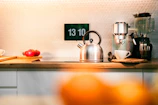 A kitchen counter with a tea kettle, oranges, and other kitchen items