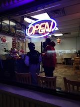 A restaurant with a neon sign that reads open