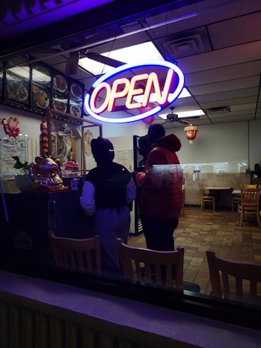 A restaurant with a neon sign that reads open