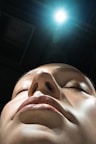 A woman with her eyes closed and a light shining on her head