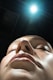 A woman with her eyes closed and a light shining on her head