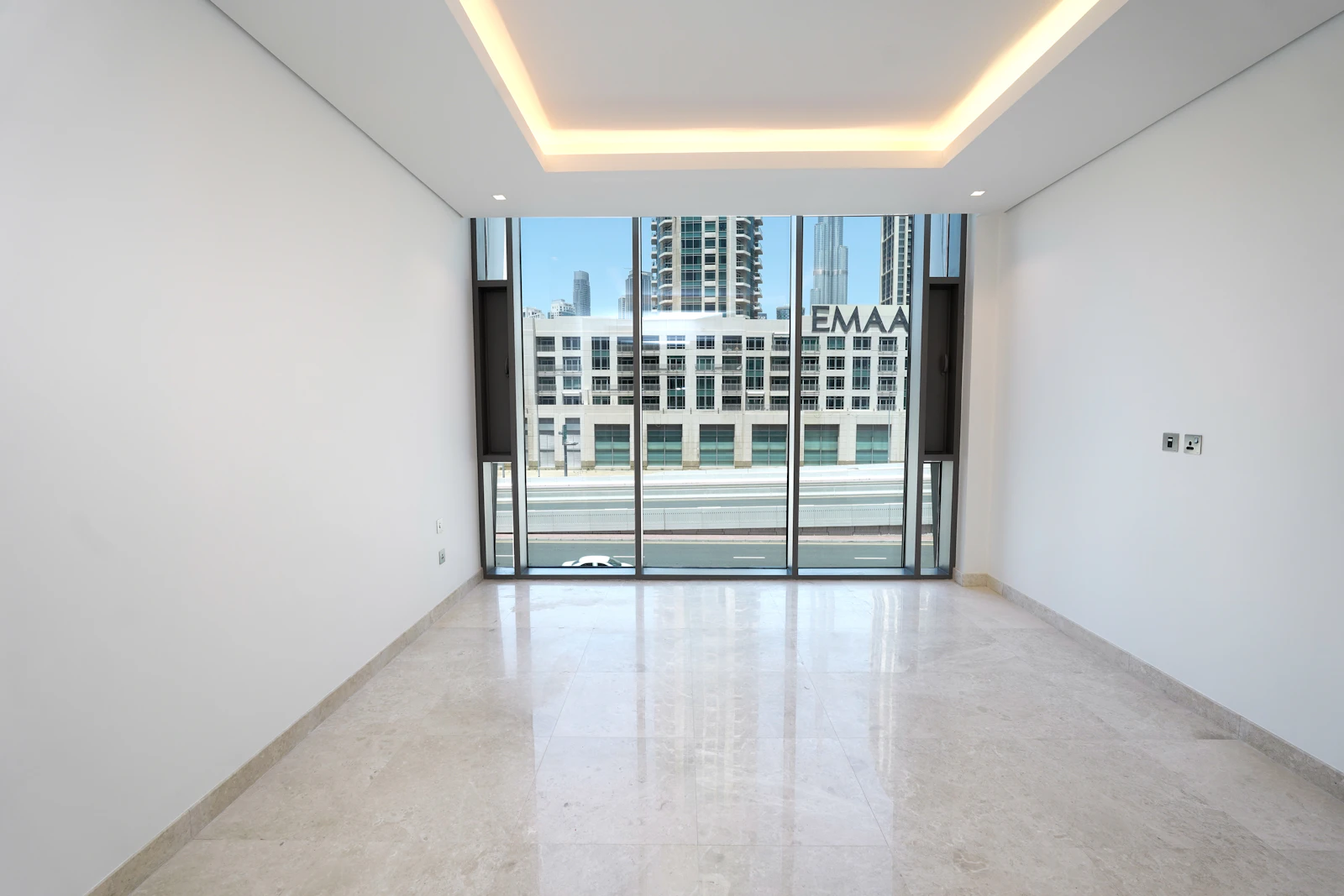 Empty stripped-back room in a Dubai villa mid-renovation with a floor-to-ceiling window and city view