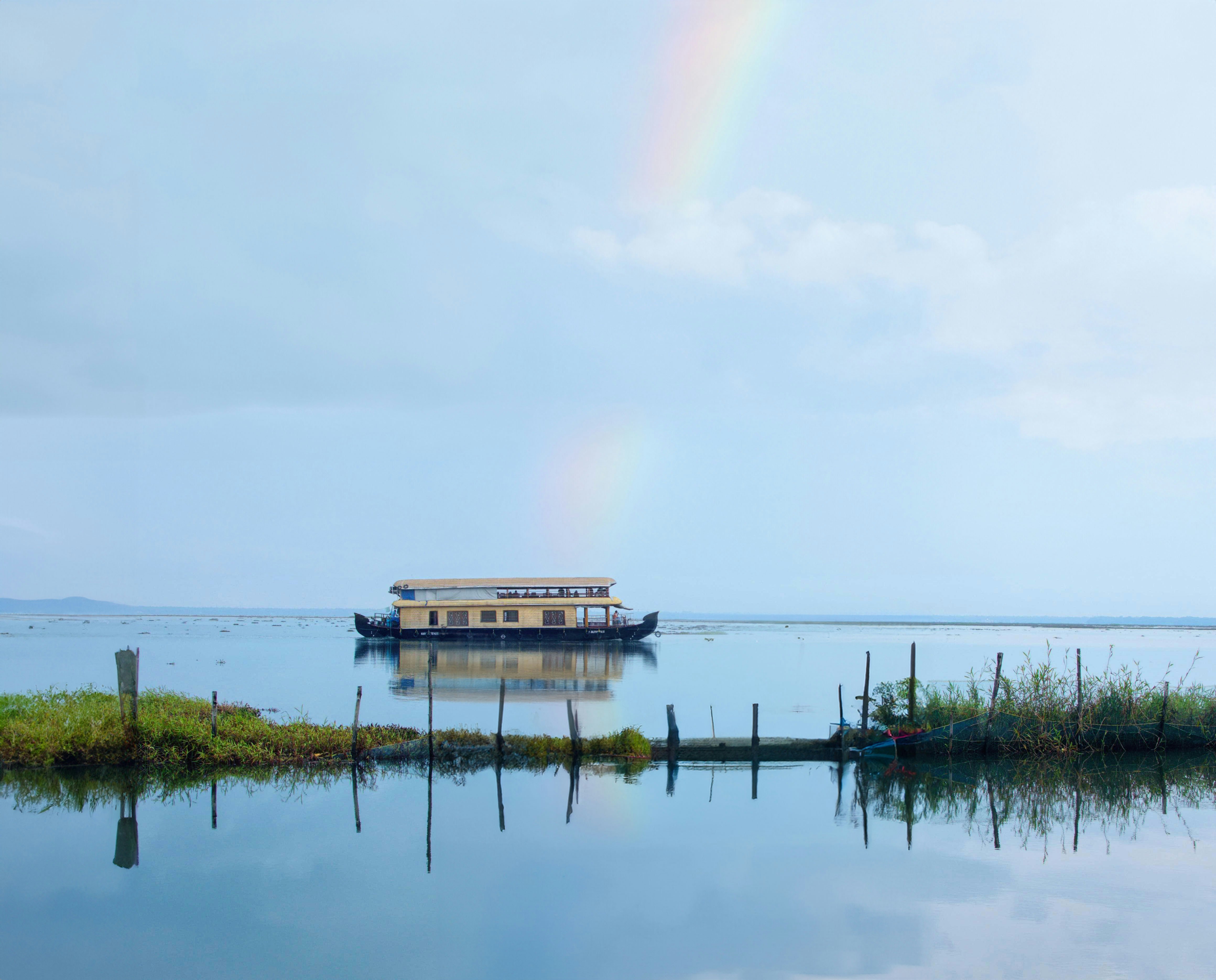 A houseboat is on the water with a rainbow in the background