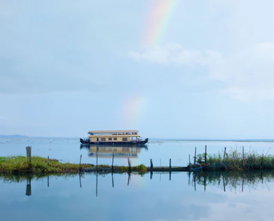 A houseboat is on the water with a rainbow in the background