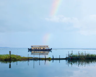 A houseboat is on the water with a rainbow in the background
