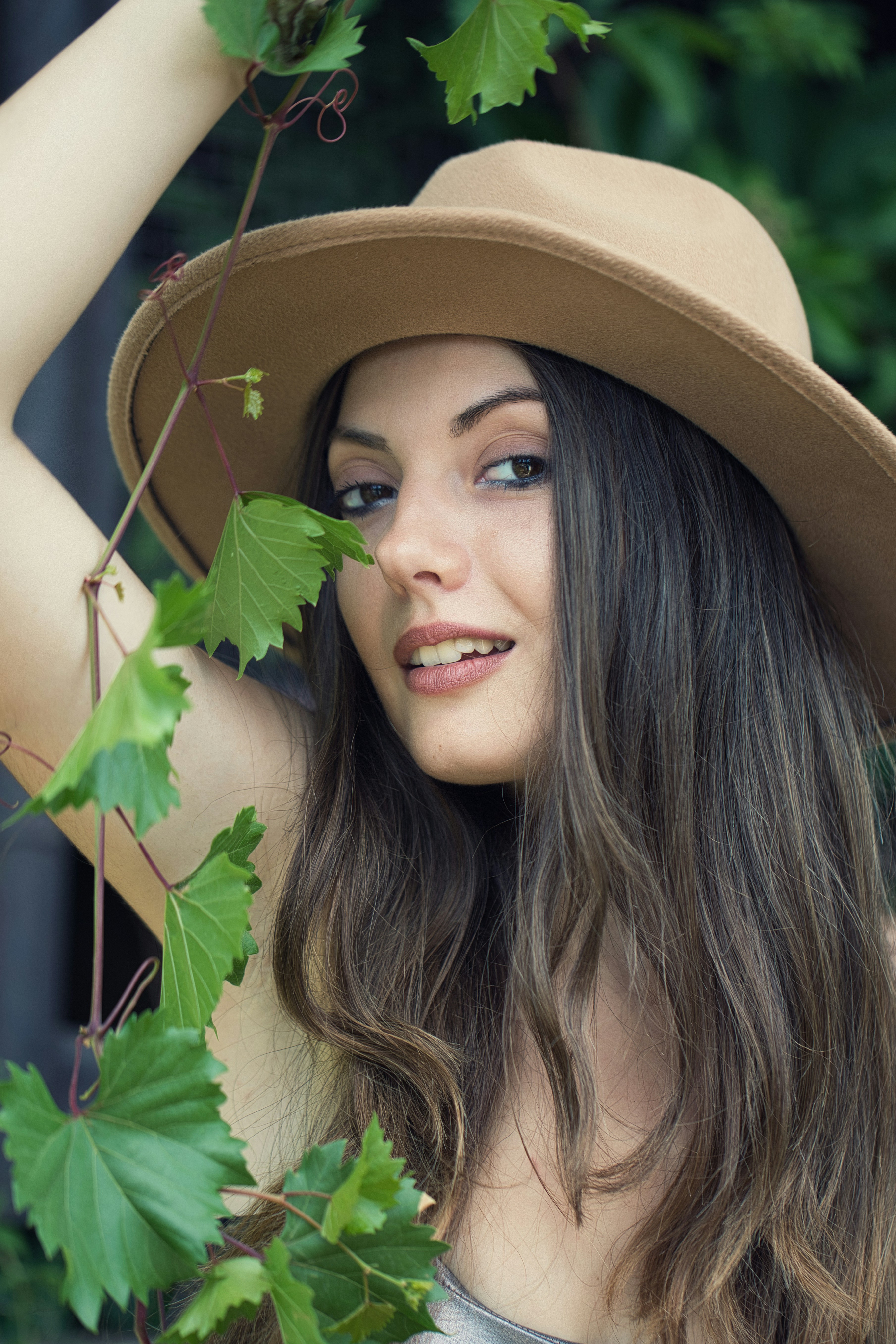 A woman wearing a hat and holding a branch