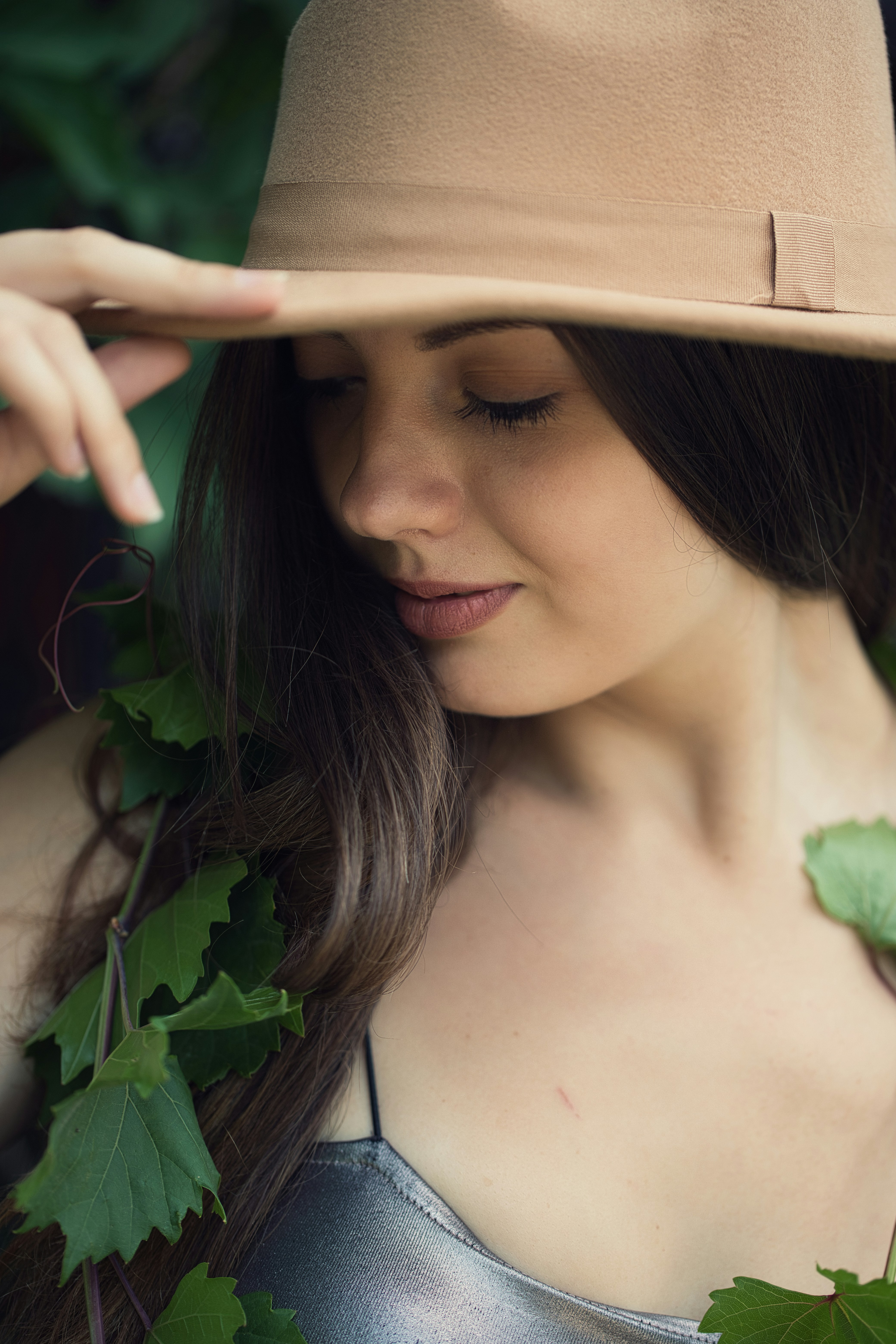 A woman wearing a hat with a green vine around her neck