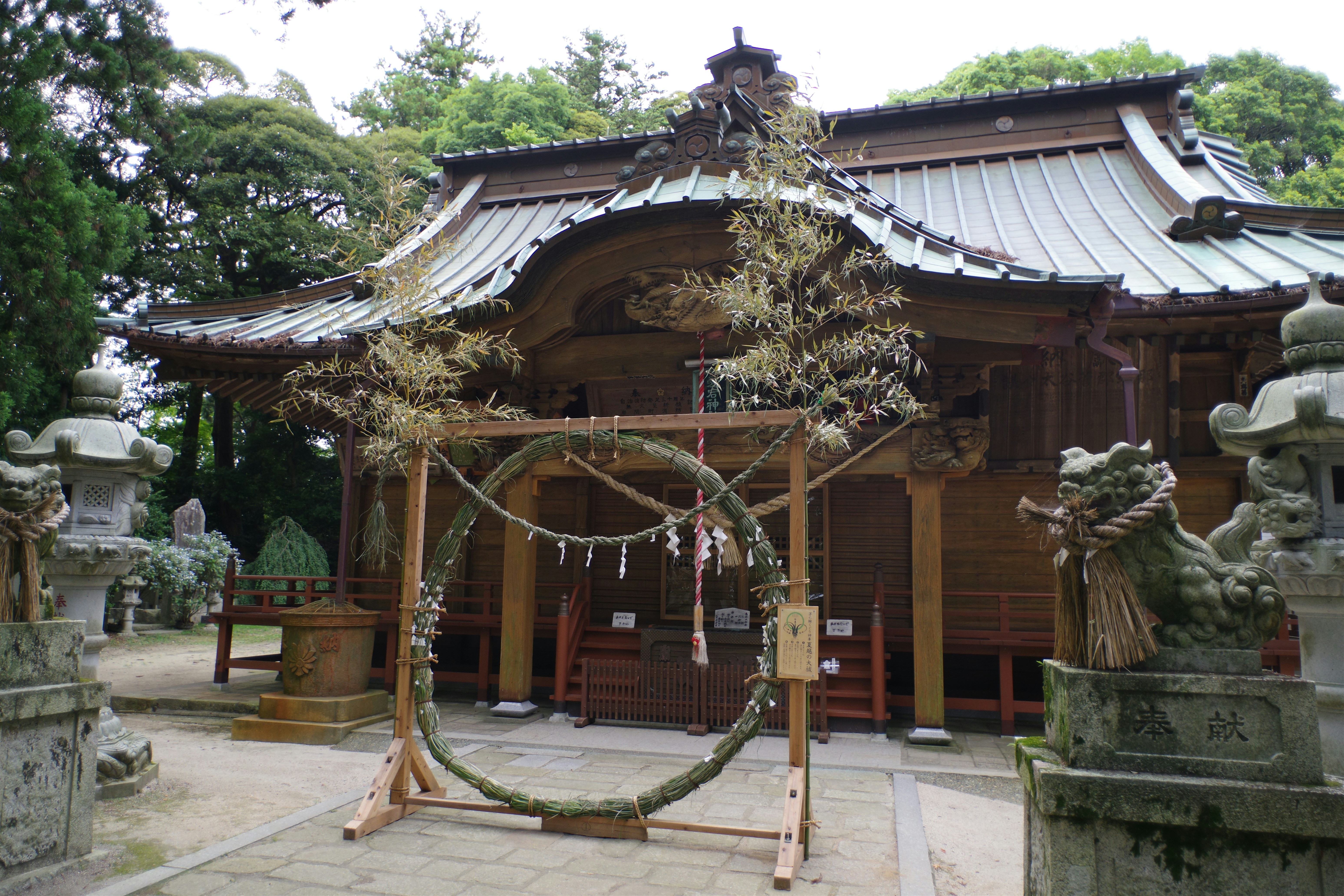 A Shinto priest in formal robes performing a purification ceremony with a haraegushi wand.