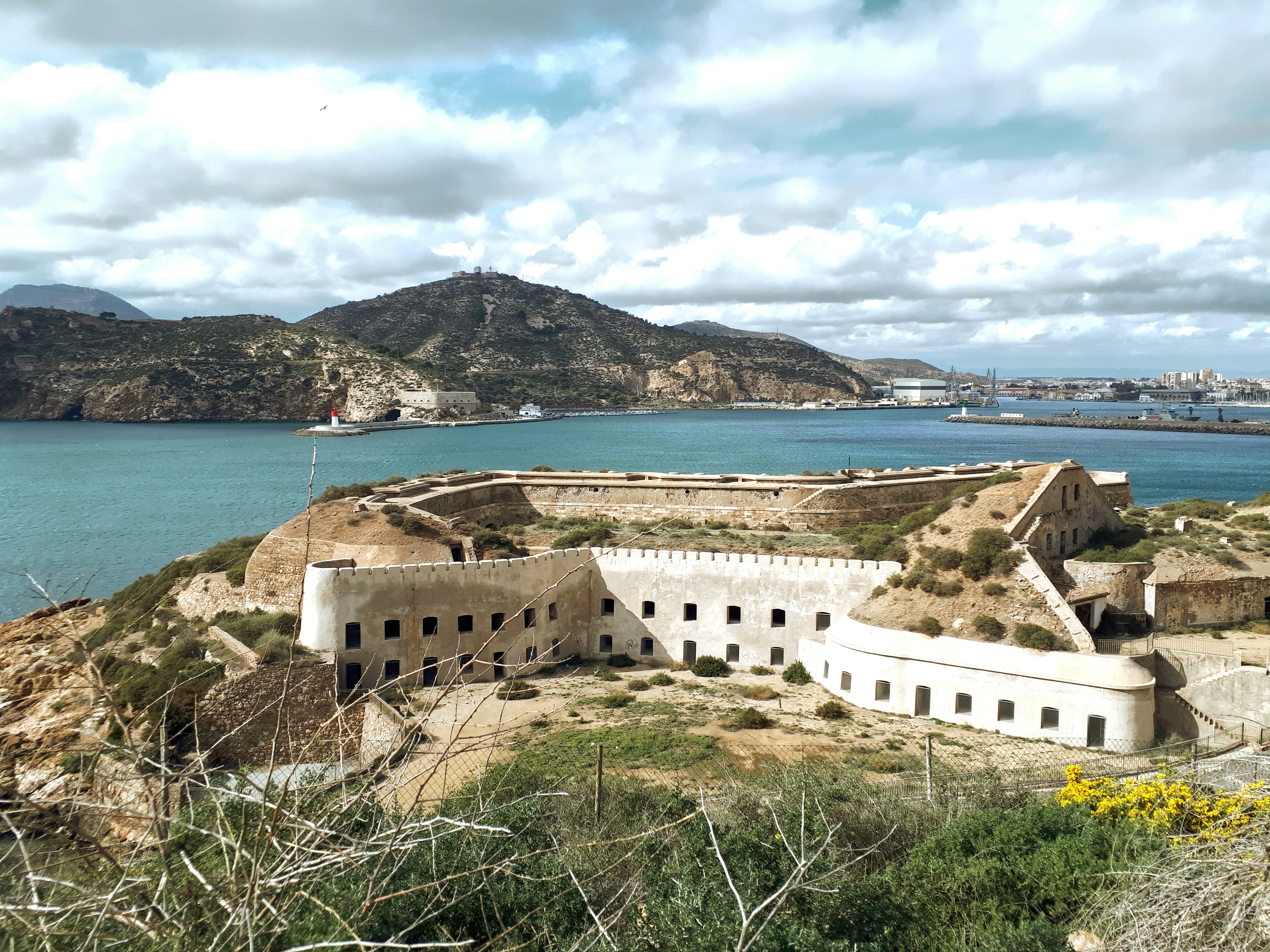 A view of a building on a hill overlooking a body of water