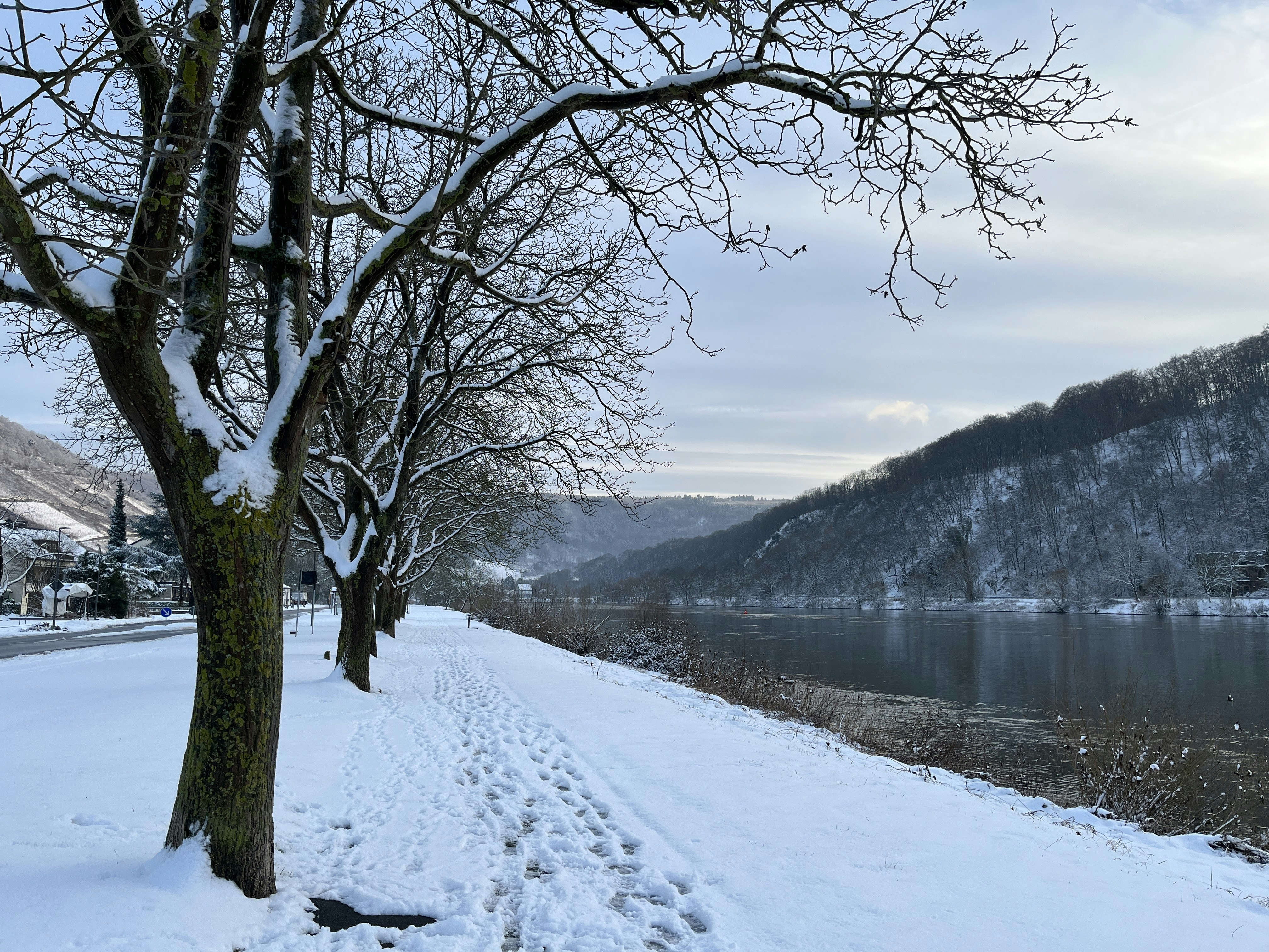 A snow covered road next to a lake