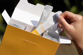 A person holding a yellow box filled with items
