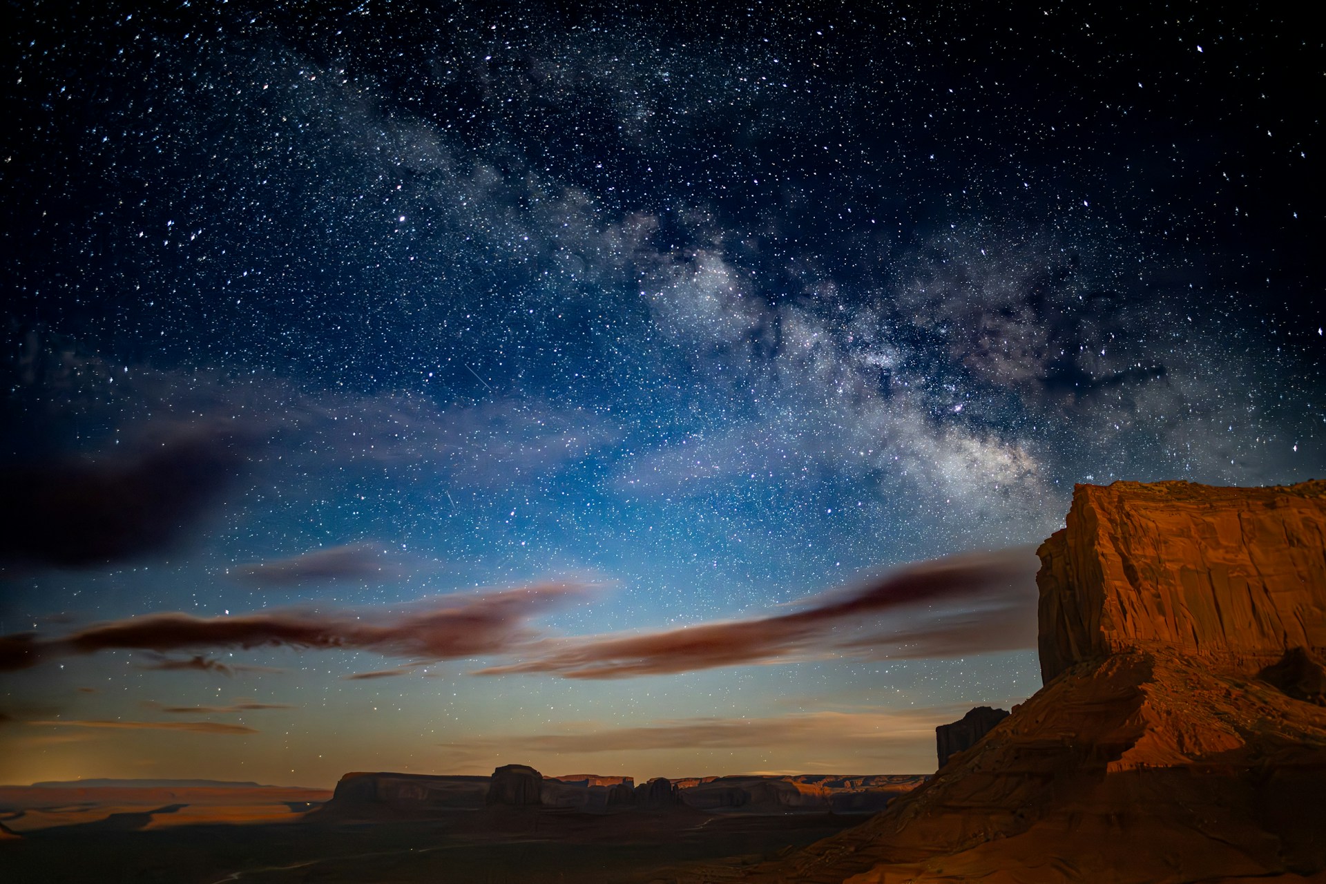 The night sky is filled with stars and clouds