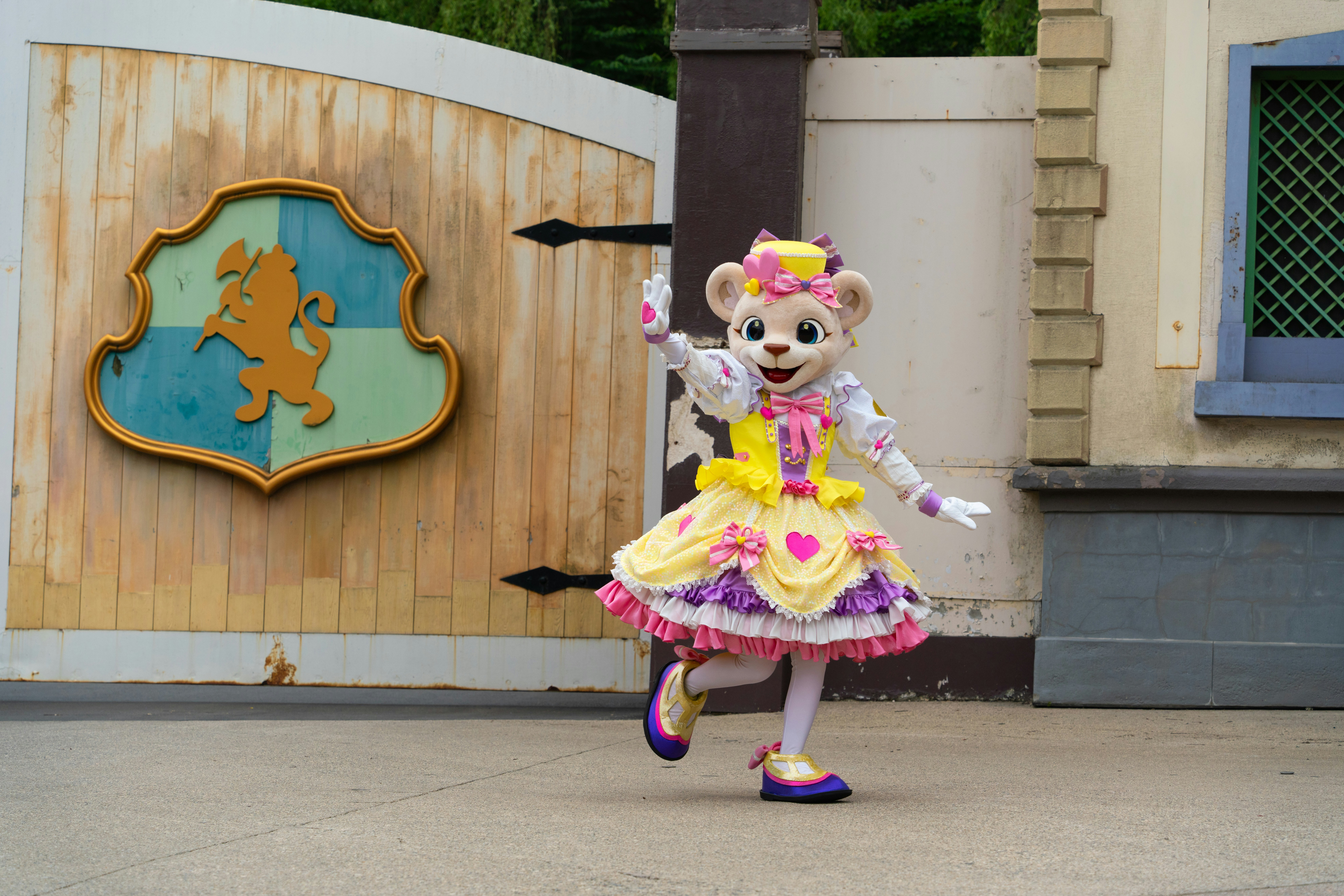 A teddy bear dressed in a dress is dancing in front of a sign