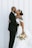 A bride and groom kissing in front of a white wall