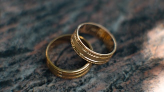 Two gold wedding rings sitting on top of a table